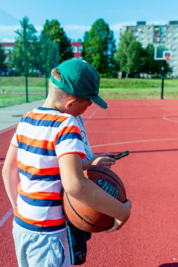 Telsiai Litvanya 08: 12 2020 Yakışıklı Çocuk Basketbol sahasında cep telefonu kullanıyor.