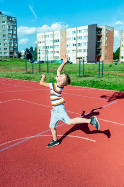 Telsiai, Litvanya 08: 12 2020 Çekici Kafkasyalı küçük basketbolcu açık havada kırmızı kortta antrenman yapıyor.