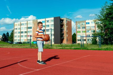 Telsiai, Litvanya 08: 12 2020 Çekici Kafkasyalı küçük basketbolcu açık havada kırmızı kortta antrenman yapıyor.