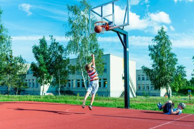 Telsiai, Litvanya 08: 12 2020 Çekici Kafkasyalı küçük basketbolcu açık havada kırmızı kortta antrenman yapıyor.