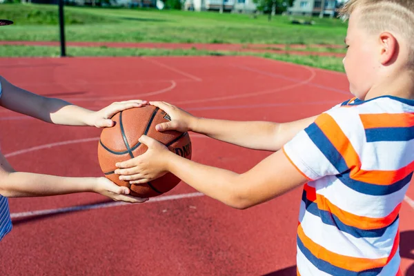 Telsiai, Litvanya 08: 12 2020 Çekici Kafkasyalı iki küçük basketbolcu açık havada kırmızı kortta antrenman yapıyor.