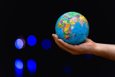 Dünya Gezegeni insanoğlunun elinde renkli lambalara karşı bulanık. İş, politika, ekoloji ve medya kavramları. Dünya gecesi soyut arkaplanı.