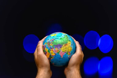 Dünya Gezegeni, insanların elinde renkli lambalara karşı bulanık. İş, politika, ekoloji ve medya kavramları. Dünya gecesi soyut arkaplanı.