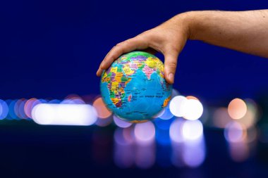 Dünya Gezegeni karanlık şehre karşı insanoğlunun elinde. İş, politika, ekoloji ve medya kavramları. Dünya günü soyut arkaplanı.