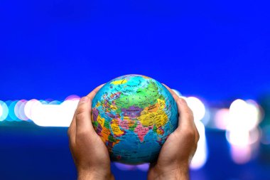 Dünya Gezegeni karanlık şehre karşı insanoğlunun elinde. İş, politika, ekoloji ve medya kavramları. Dünya günü soyut arkaplanı.