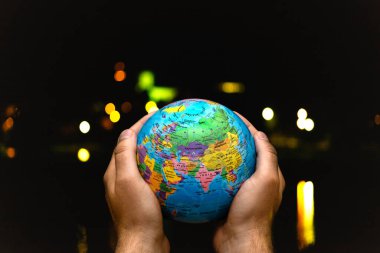 Dünya Gezegeni karanlık şehre karşı insanoğlunun elinde. İş, politika, ekoloji ve medya kavramları. Dünya günü soyut arkaplanı.