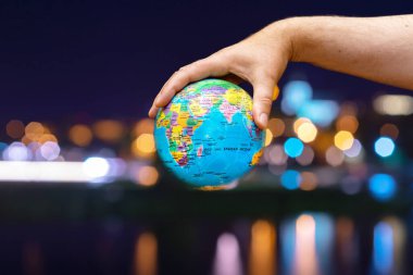 Dünya Gezegeni karanlık şehre karşı insanoğlunun elinde. İş, politika, ekoloji ve medya kavramları. Dünya günü soyut arkaplanı.