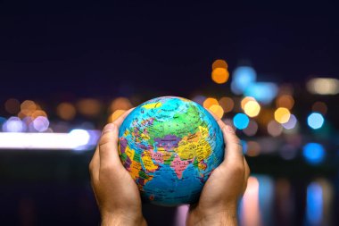 Dünya Gezegeni karanlık şehre karşı insanoğlunun elinde. İş, politika, ekoloji ve medya kavramları. Dünya günü soyut arkaplanı.