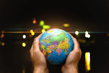 Dünya Gezegeni karanlık şehre karşı insanoğlunun elinde. İş, politika, ekoloji ve medya kavramları. Dünya günü soyut arkaplanı.