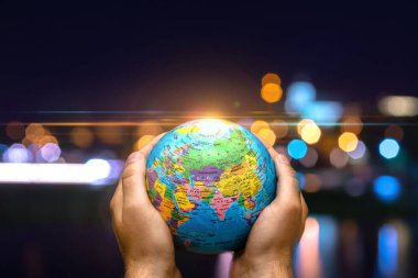 Dünya Gezegeni karanlık şehre karşı insanoğlunun elinde. İş, politika, ekoloji ve medya kavramları. Dünya günü soyut arkaplanı.