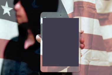 Gri kazaklı bulanık bir adam fotokopi alanı için boş ekranlı tablet bilgisayar tutuyor. Arkasında ABD bayrağı var. Seçmeli odak noktası. Görüntü ayarlı..