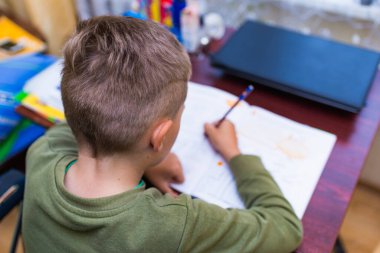 Kafkasyalı bir öğrencinin evdeki bir masada otururken ödev yapmasını yakından izle. Kitap okumak ve dersleri tamamlamak. Bir okul çocuğu ödevini yapar. Eğitim kavramı.