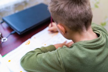 Kafkasyalı bir öğrencinin evdeki bir masada otururken ödev yapmasını yakından izle. Kitap okumak ve dersleri tamamlamak. Bir okul çocuğu ödevini yapar. Eğitim kavramı.