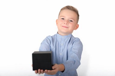 Mavi gömlekli, gülümseyen beyaz çocuk elinde siyah bir kutu tutuyor. Kutu ön tarafta. İzole edilmiş beyaz arka plan.