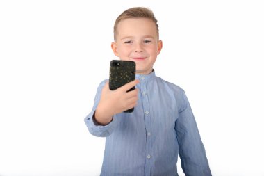 Mavi gömlekli Avrupalı Çocuk beyaz arka planda izole bir şekilde telefonda selfie çekiyor..