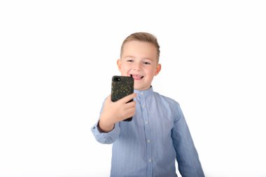 Mavi gömlekli Avrupalı Çocuk beyaz arka planda izole bir şekilde telefonda selfie çekiyor..