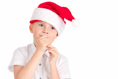 Beyaz arka planda Noel şapkası takan sevimli bir çocuk. Sevimli ve düşünceli.
