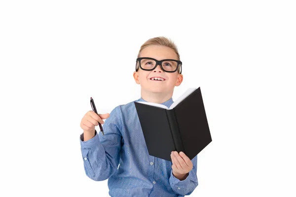 白い背景にノートのペンを手にした魅力的な白人の少年 眼鏡をかけた少年 子供は学校に行く準備ができています ロイヤリティフリーのストック画像