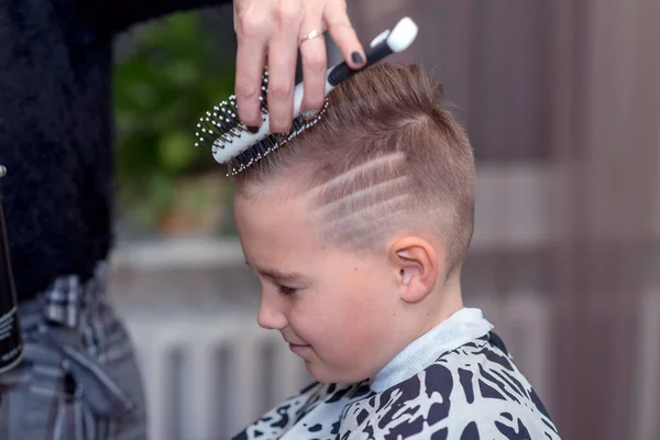 Side view Nice european boy getting hairstyle in barbershop.hairdresser  makes a hairstyle for a boy Stock Photo - Alamy