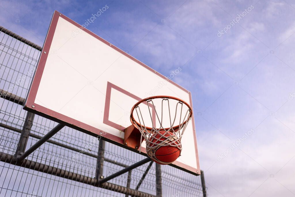 basketball white old board with basket hoop against blue cloudy sky.