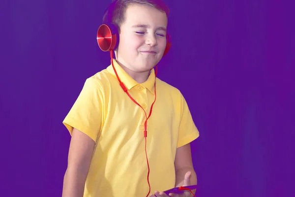 彼の携帯電話を使用して 一人で音楽を聴いたり ビデオを見て 1人の若い学校の少年のクローズアップ パープル霧のトーンの背景 — ストック写真