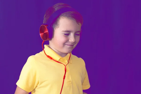 彼の携帯電話を使用して 彼の携帯電話を使用して 若い学校の少年の目を閉じて 音楽を単独で聞くか ビデオを見て パープル霧のトーンの背景 — ストック写真