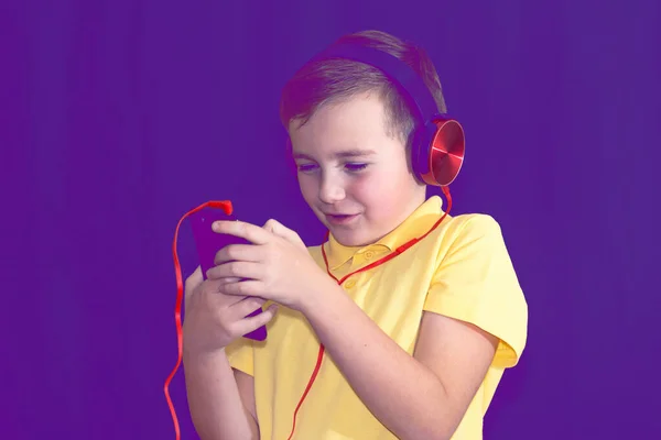 接近一个小学生 用他的电话 一个人听音乐或看视频 紫色雾蒙蒙的背景音乐 — 图库照片