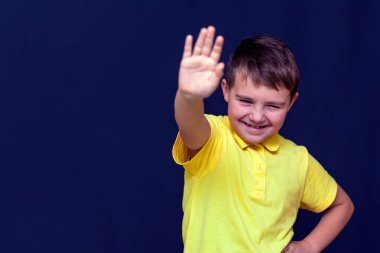 Küçük 9 'lu çocuk elini uzatıp dur işareti yapıyor. Mavi stüdyo arka planı..