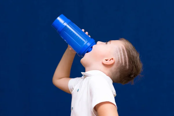 サイドビューを閉じるアップ若いですCaucasian男の子身に着けている白いTシャツ保持水ボトル子供飲む上の青 — ストック写真