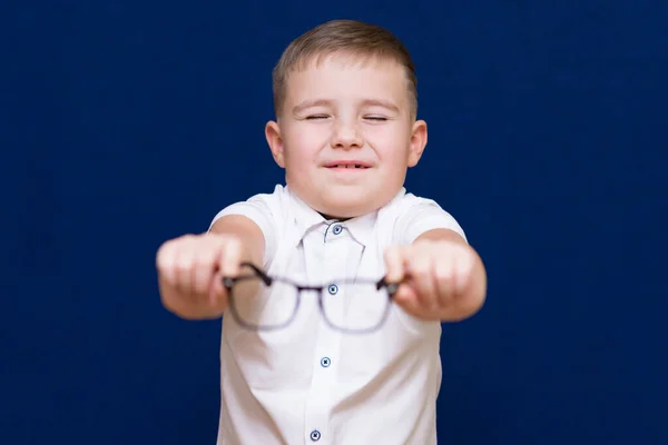 Retrato Chico Caucásico Sostiene Muestra Gafas Sobre Fondo Azul Oscuro Fotos de stock libres de derechos