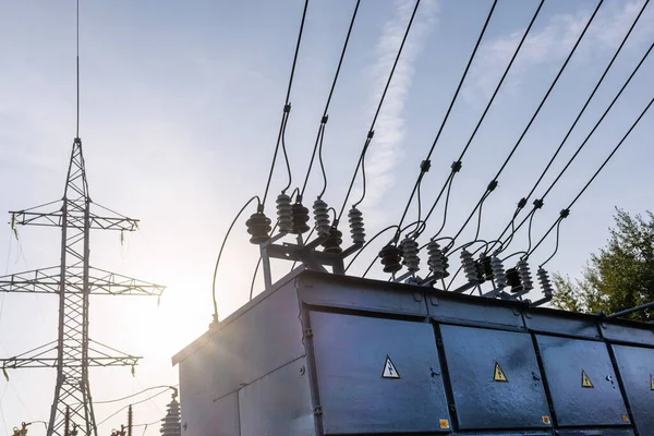 Electric power transmission lines in the evening. High voltage switchgear and equipment of power plant.