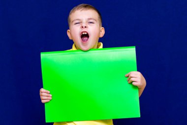 Mutlu, hoş, sakin, beyaz çocuk mavi arka planda senin için bir poster tutuyor.