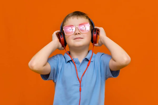 Atrakcyjny Młody Dzieciak Czerwonych Okularach Słucha Muzyki Czerwonymi Słuchawkami Pomarańczowym — Zdjęcie stockowe