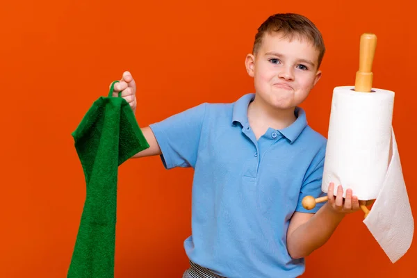 Portrait of a Caucasian boy. The boy holds a paper towel, the other hand used to towel. Which is better. Housewives concept.