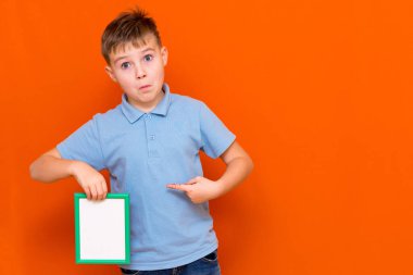Turuncu arka planda izole edilmiş beyaz tişörtlü öğrenci portresi. Kopyalama alanı oluşturun. Metin veya resim için yeri olan boş beyaz reklam panosuna gösterir.