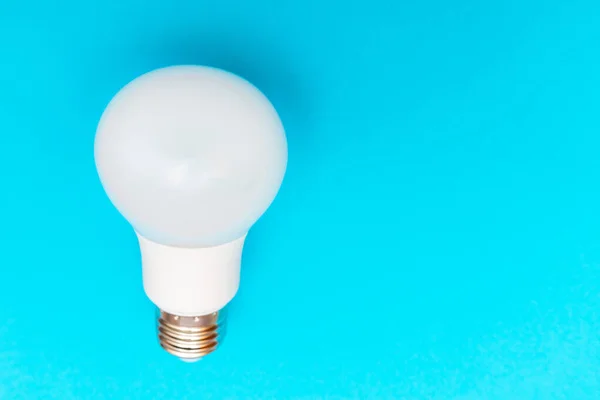LED lamp and fluorescent lamp flat lay on blue background. LED bulb. White energy-saving light bulb.Copy space