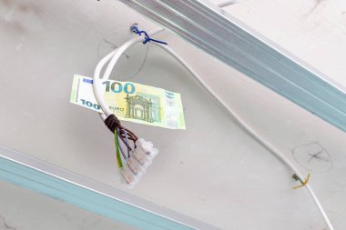 Aydınlatma için elektrik tesisatı, eski bir dairedeki kablolara asılı 100 euro kağıt fatura, kablolu ve konaklamalı konut aydınlatma yenilemesi.