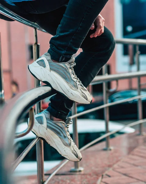 Hombre sentado en una valla con jeans y zapatillas —  Fotos de Stock