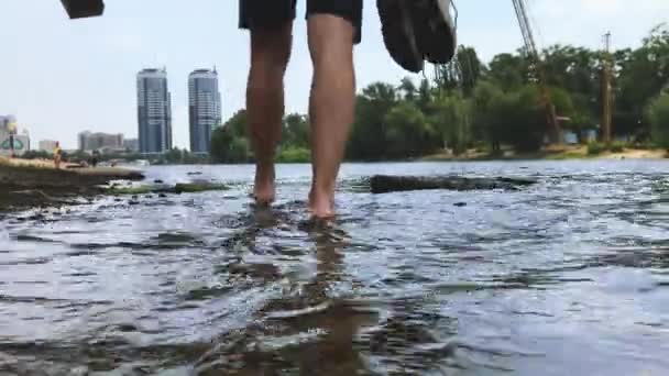 Adam elinde spor ayakkabılarla sahilde yürüyor.. — Stok video