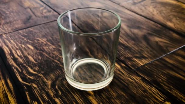 Los cubos de hielo se mueven en un vaso empañado sobre un fondo de mesa — Vídeos de Stock