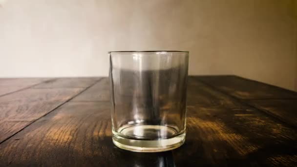 Cubos de gelo se movem em um vidro enevoado em um fundo de mesa — Vídeo de Stock