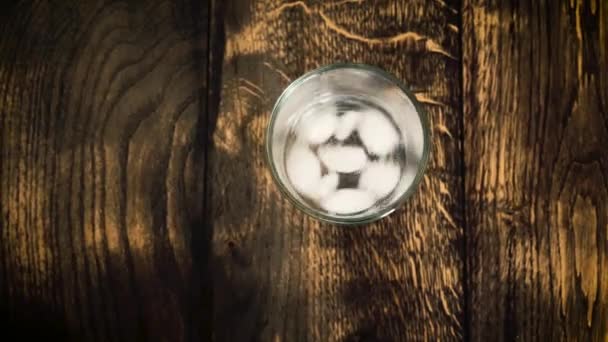 Eiswürfel bewegen sich in einem vernebelten Glas auf einem Tischhintergrund — Stockvideo