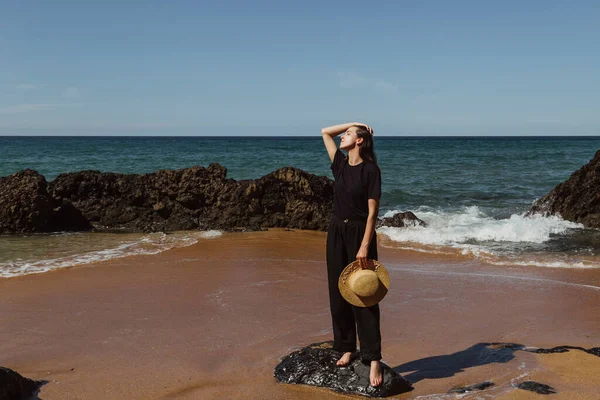 Girl on a background of the sea in black clothes. A girl on a background of the Spanish landscape. A woman on a background of blue ocean.The girl in black clothes at coast sea, blue sky.Close-up a young girl in black clothes is standing by the sea.