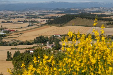Güneşli bir yaz gününde Dağ Köyü. İspanya Dağları 'ndaki küçük bir köye manzaralı. Dağlar arasında tarlaları ve köyleri olan yeşil bir vadi..