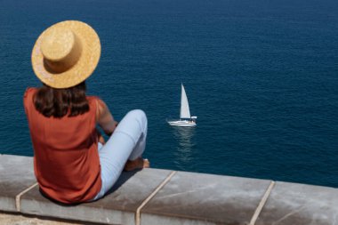 Dikiz aynası: taştan bir terasta uzun siyah saçlı bir kadın. Tropik bir tatil. Dinlen ve eğlen. Deniz manzaralı arka plan manzaralı bir kadın..