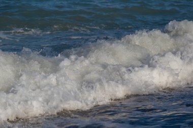 Deniz dalgasının beyaz tepesi. Sahilde bir dalga..