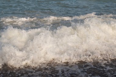 Deniz dalgasının beyaz tepesi. Sahilde bir dalga..