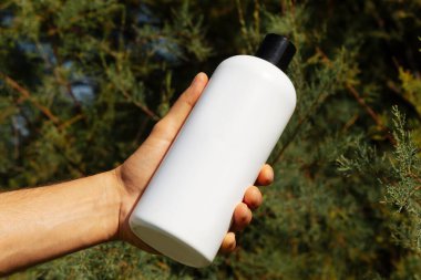 Yeşil arka planda izole edilmiş beyaz şişeli bir adam. Adamın eli beyaz bir şişe tutuyor..