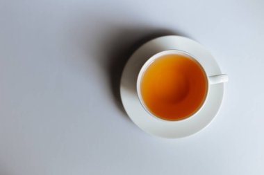 Fotokopi alanı olan bir fincan sıcak çayın en üst görüntüsü. Sıcak çay beyaz arka plana yerleştirilmiş beyaz bir bardaktadır. Mesaj için yer var. Beyaz arkaplan.