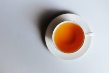 Fotokopi alanı olan bir fincan sıcak çayın en üst görüntüsü. Sıcak çay beyaz arka plana yerleştirilmiş beyaz bir bardaktadır. Mesaj için yer var. Beyaz arkaplan.